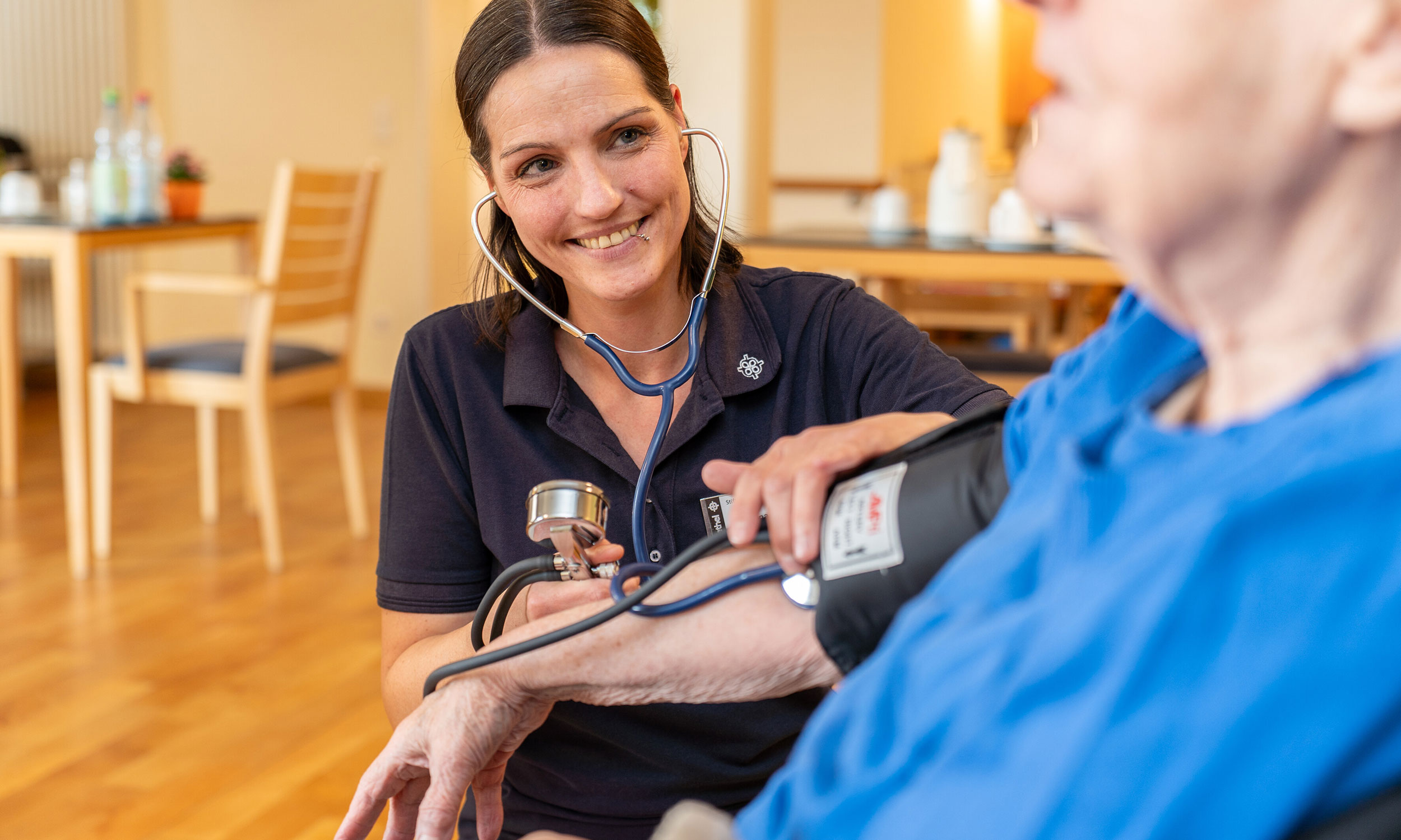 Pflegekraft misst bei einem Bewohner des Breipohls Hof den Blutdruck 