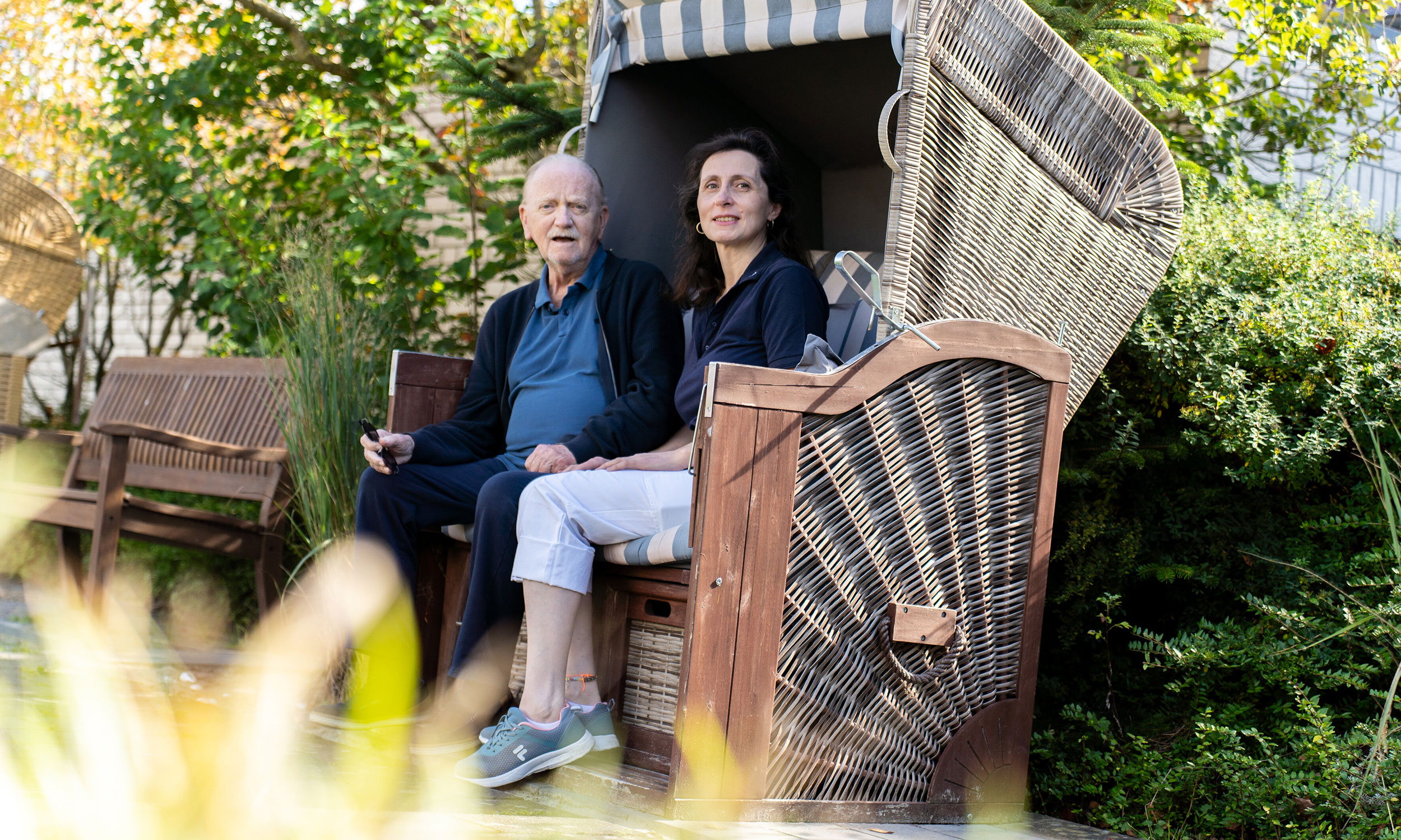 Ein Bewohner des Breipohls Hof sitzt im Garten mit einer Betreuerin in einem Strandkorb